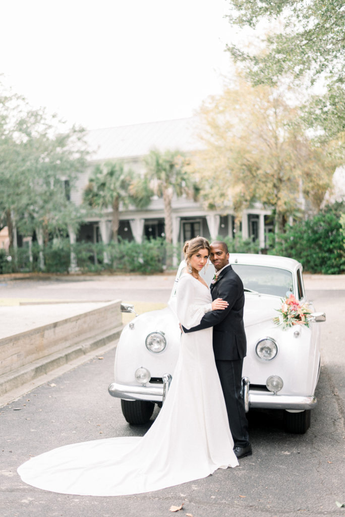 Bride and groom holding each other in front of a Bentley in Charleston South Carolina during their micro wedding