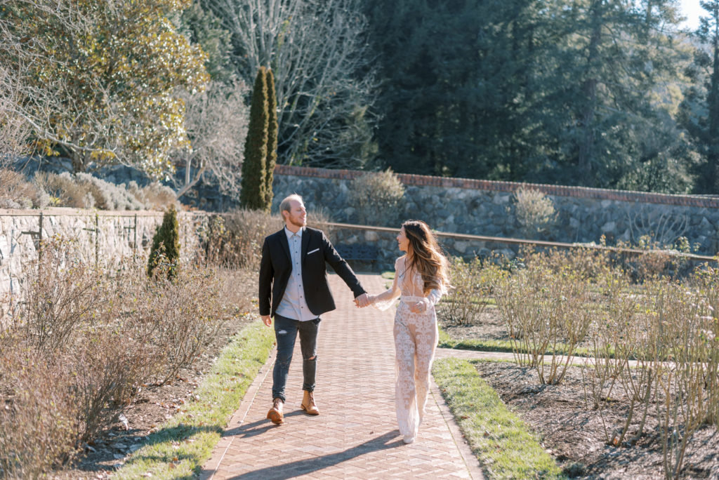 Couple running through the gardens during their winter Engagement session at The Biltmore