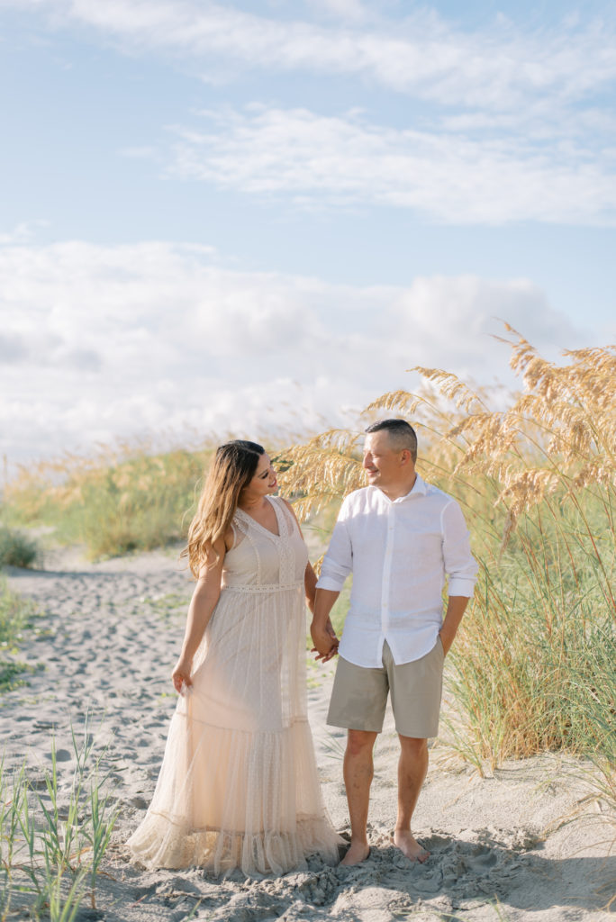 Husband and wife on Folly Beach South Carolina wearing khaki and white and an ivory lace dress