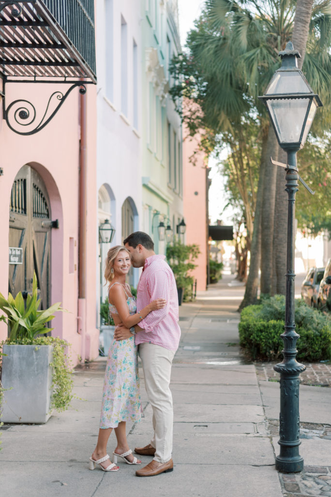Man kissing his fiancé on Rainbow Row at sunset in Charleston SC