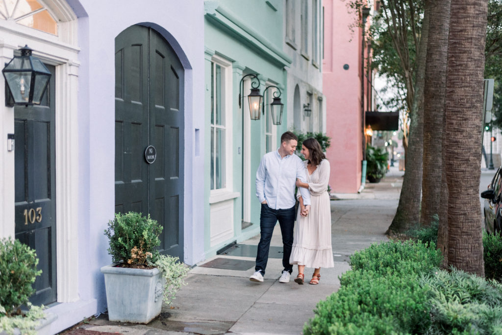 Married couple holding hands walking on Rainbow Row in Charleston South Carolina at sunrise in October