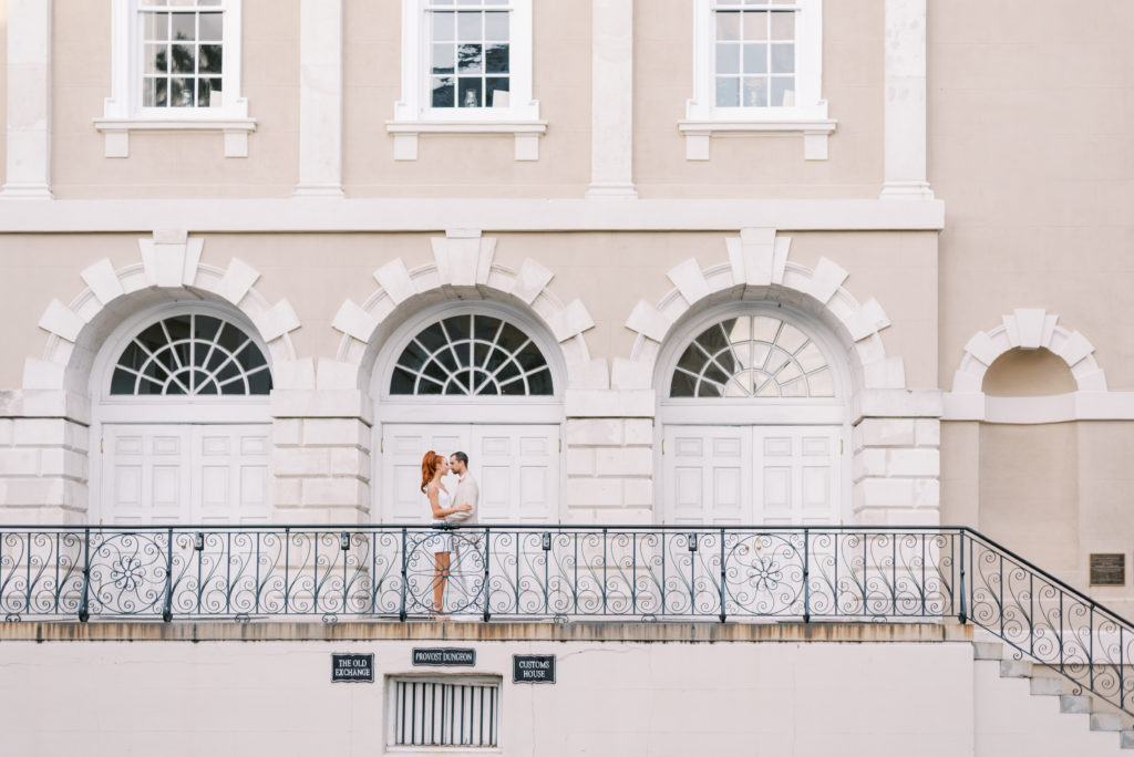 Married couple kissing on the steps on Broad Street in Charleston SC wearing white