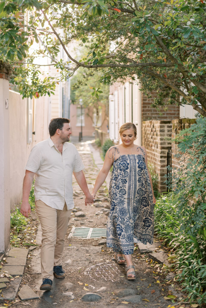 Engaged couple walking through alleyway in historic downtown Charleston