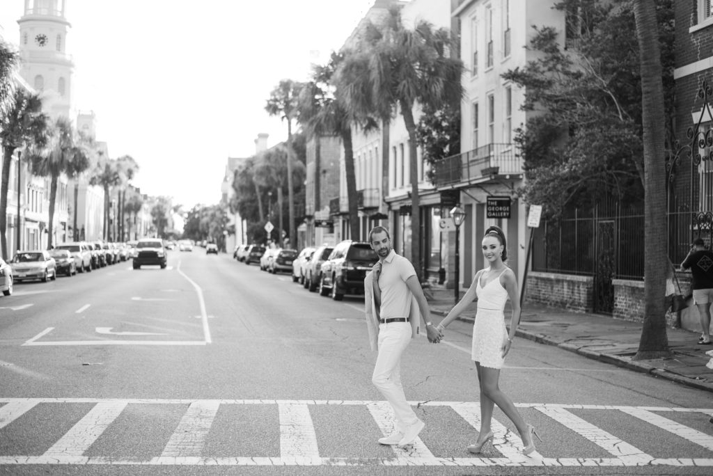 black and white couple crossing broad street in charleston at sunset