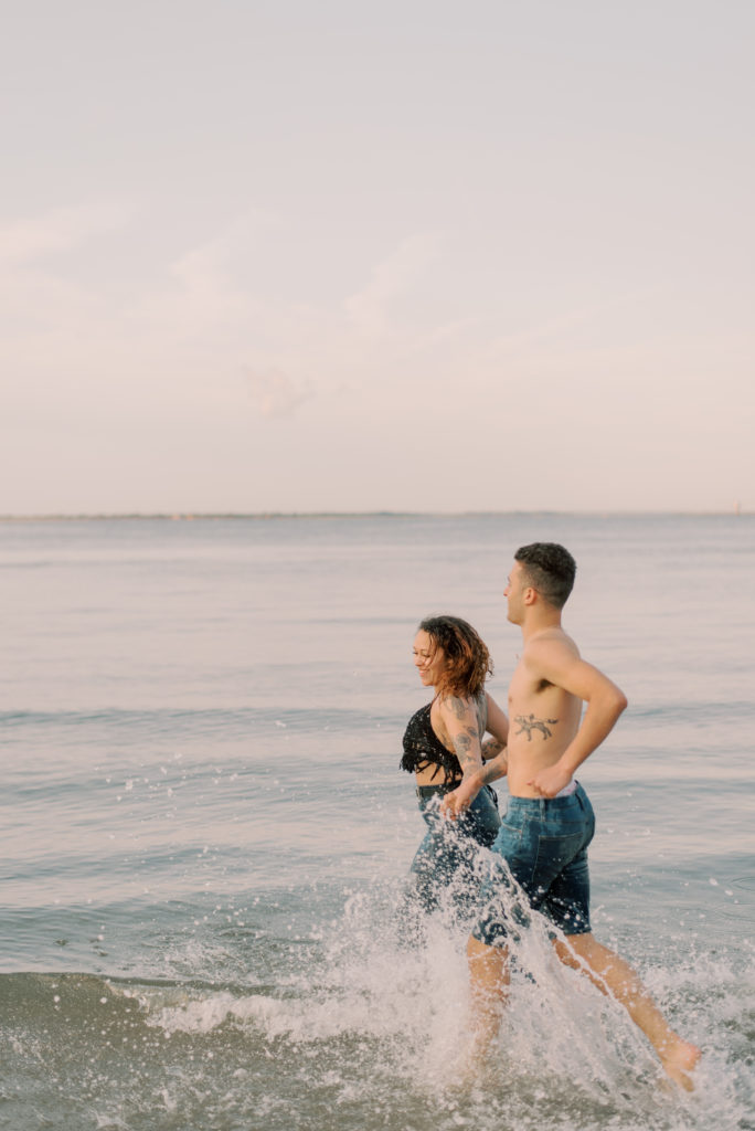 married couple splashing through water at Sullivans Island Beach at sunrise