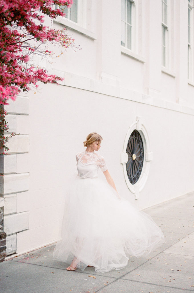 film portrait of bride beside pink flowers on the street in Charleston photographed by Kelsey Halm Photography