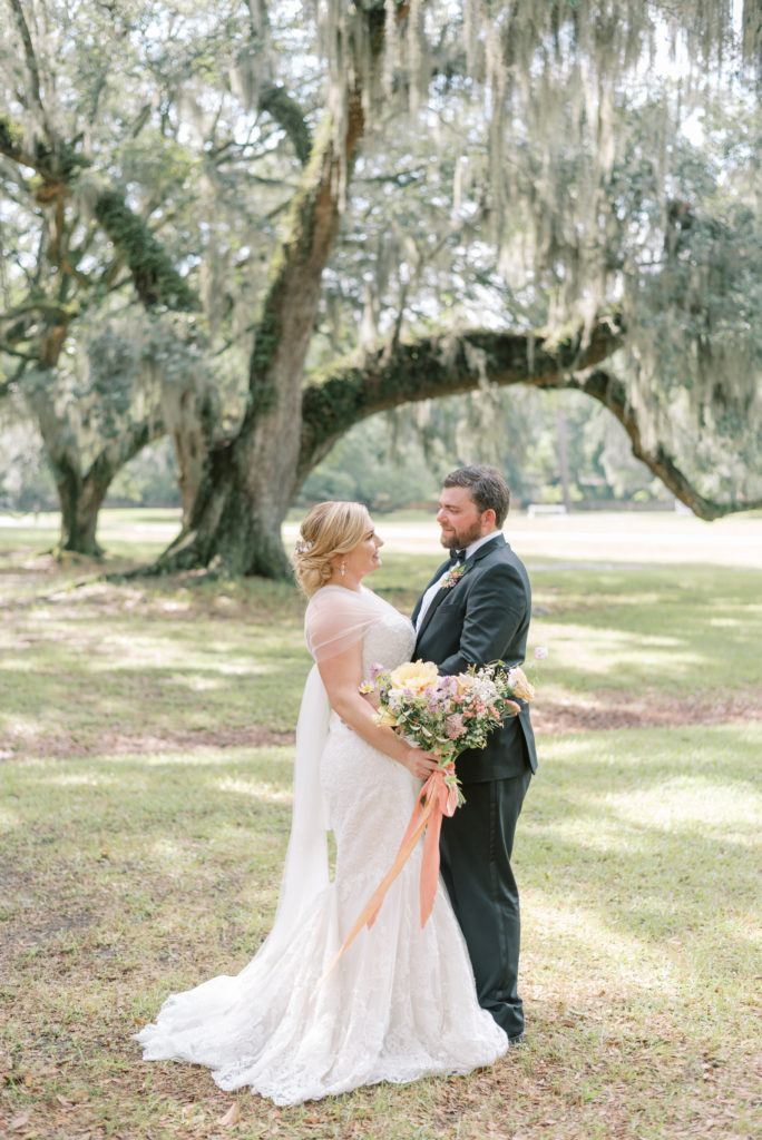 Bride and groom hugging under spanish moss live oak at Middleton Place with pastel bouquet