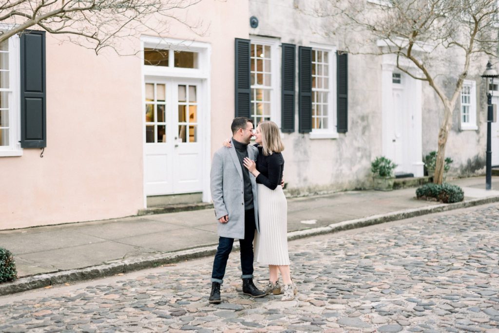 Engaged couple kissing on a cobblestone street in Charleston during the winter