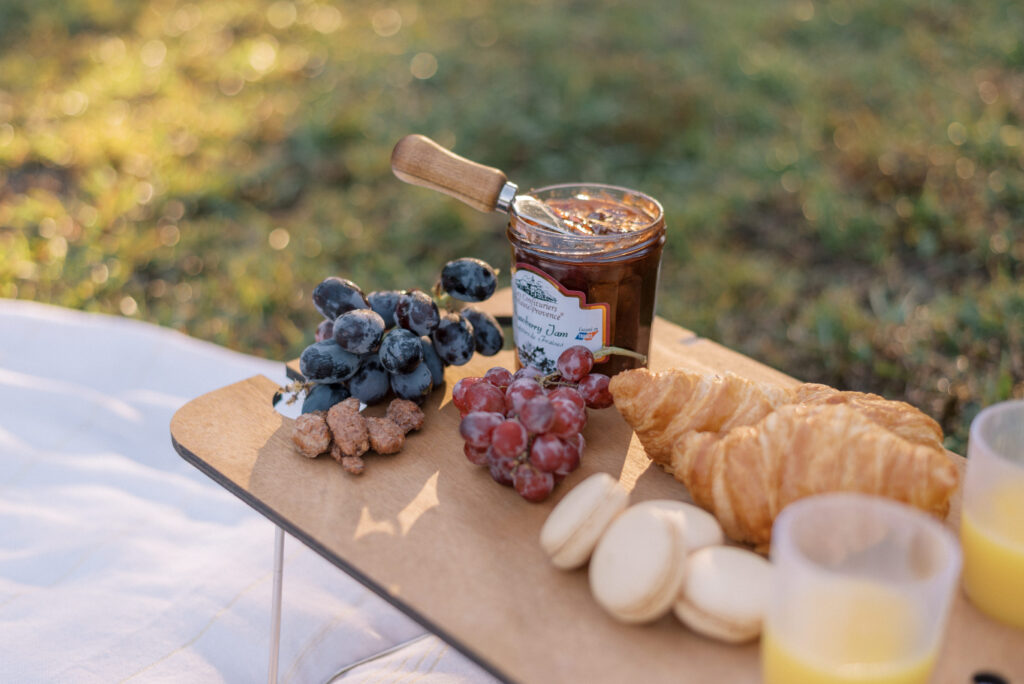 picnic setup in the early morning sun in Hampton park with grapes and jelly and croissants and macrons 