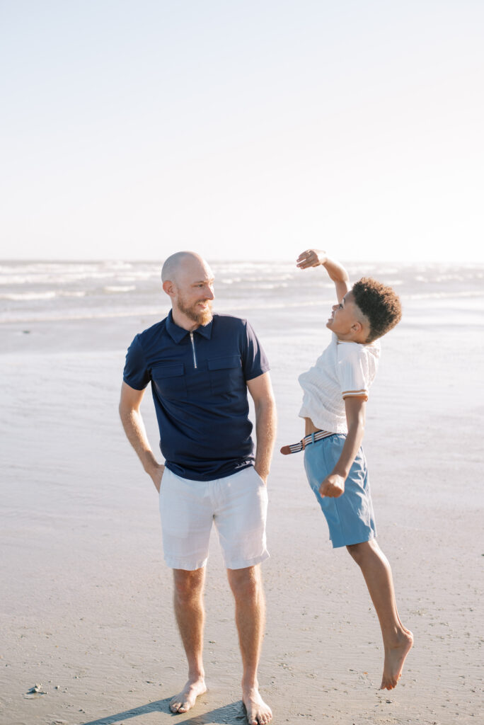 A playful moment on Isle of Palms beach as a young boy jumps in an attempt to be taller than his father. This lighthearted image showcases the fun and affection shared between a father and his son.