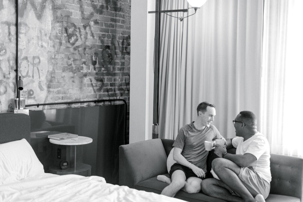 married gay couple share coffee together in their hotel room