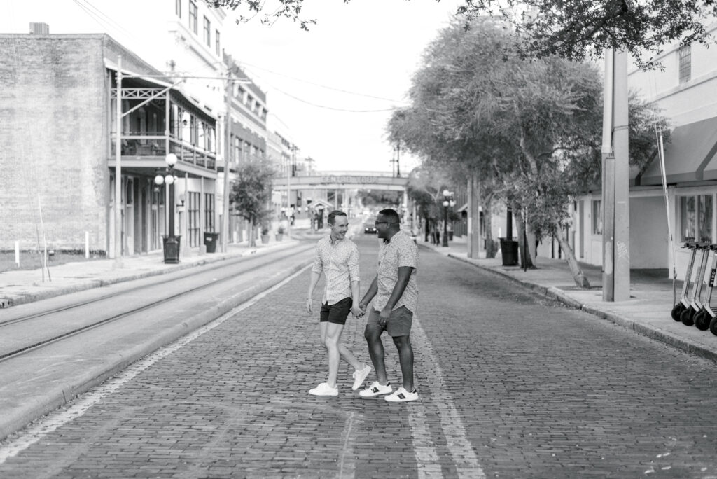 partners hold hands and cross a brick street in Ybor City