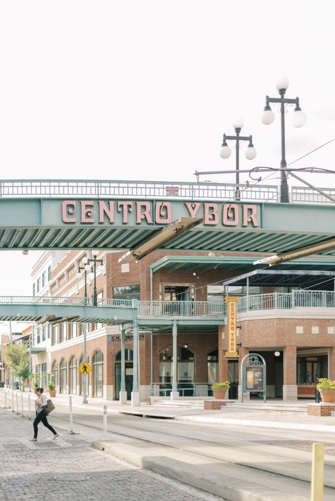 woman crossing the street under the Centro Ybor sign