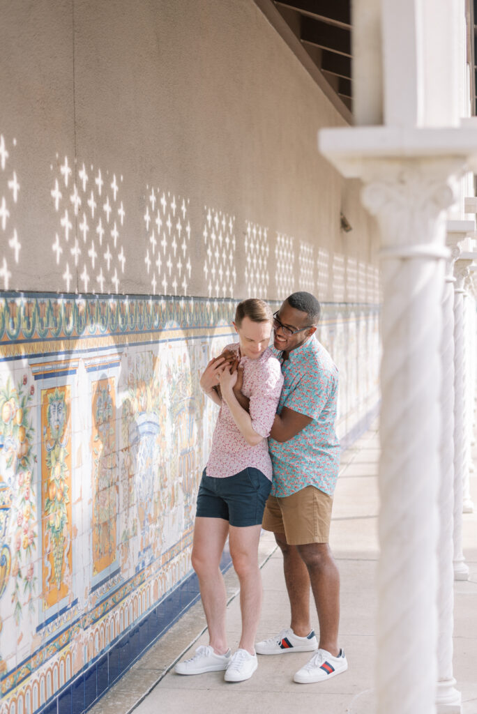 married couple lean on each other in front of tile wall