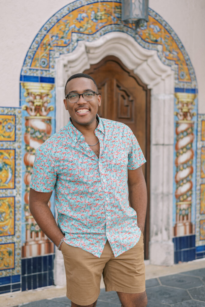 portrait of a man in a colorful shirt in front of bright tile wall and wood door