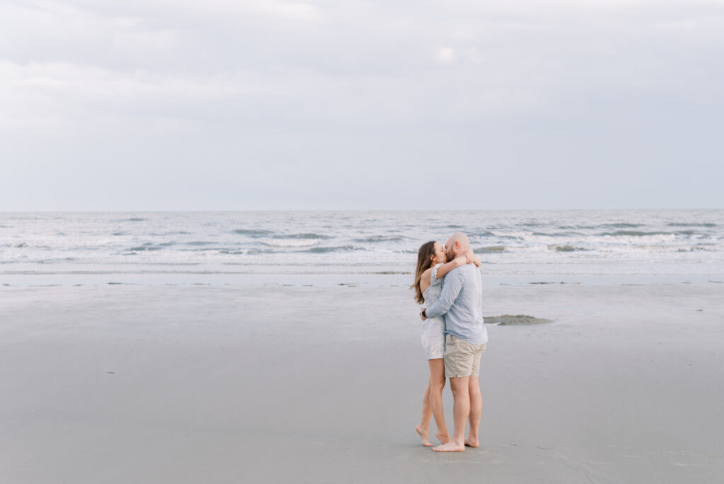 newly engaged couple share romantic kiss and embrace on the beach at kiawah island 