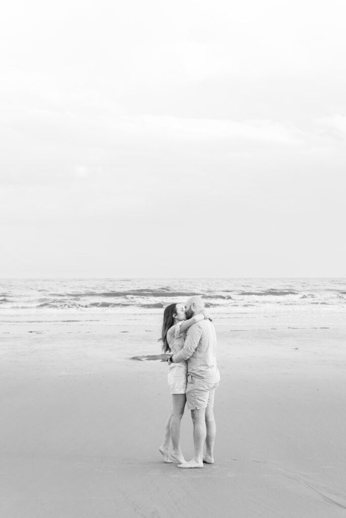 engaged couple kiss on the beach at kiawah captured in black and white