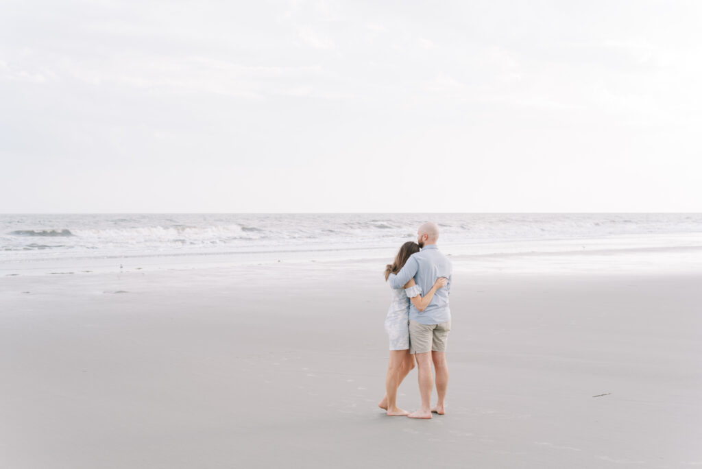 engaged couple hug and look out towards the ocean on kiawah