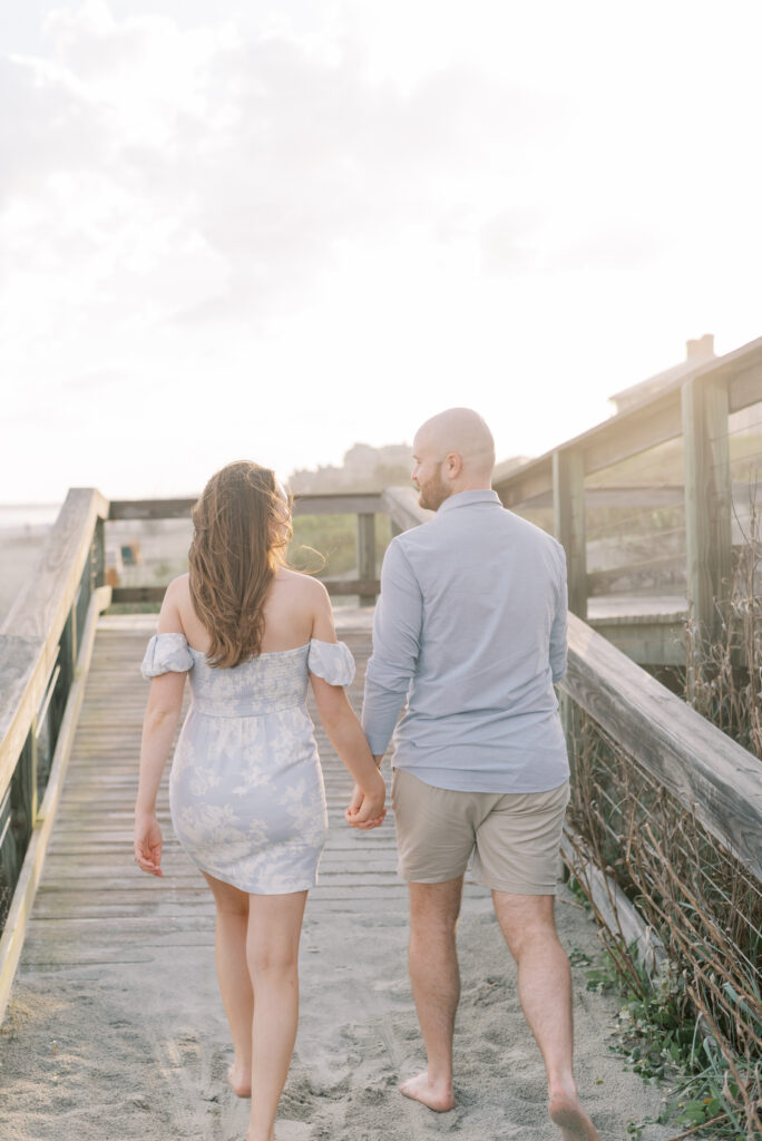 engaged couple walk up a boardwalk on the beach at kiawah