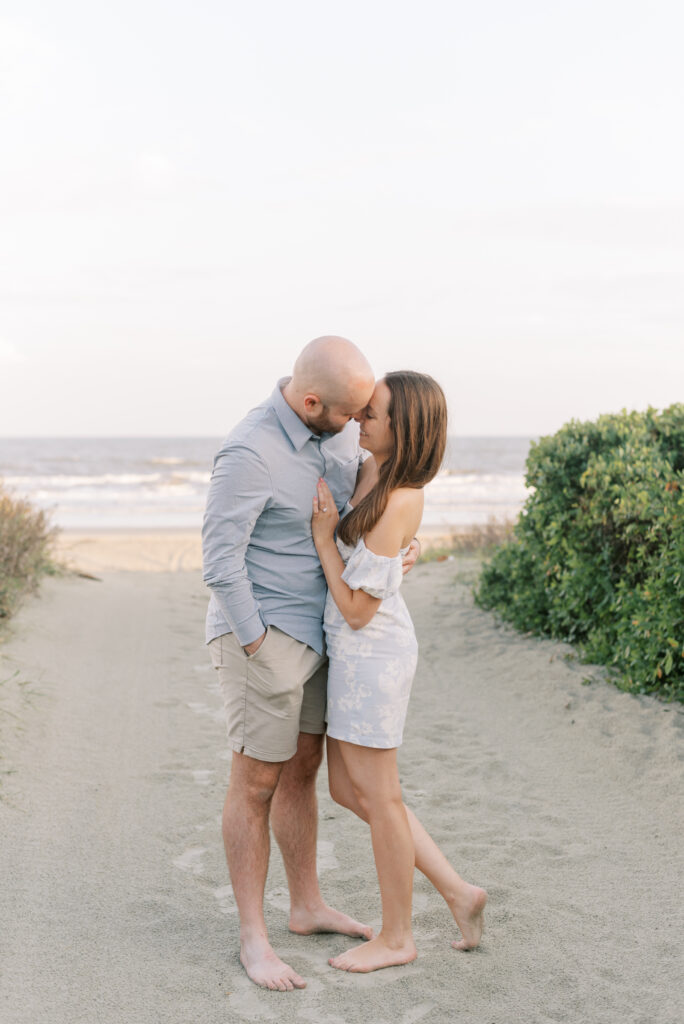 newly engaged couple lean together and smile on the beach at kiawah