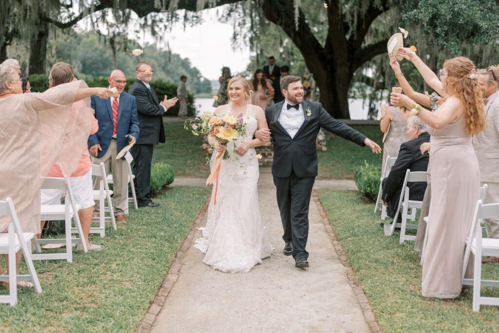 Newlyweds walk down the aisle at Middleton Place as guests throw flower petals