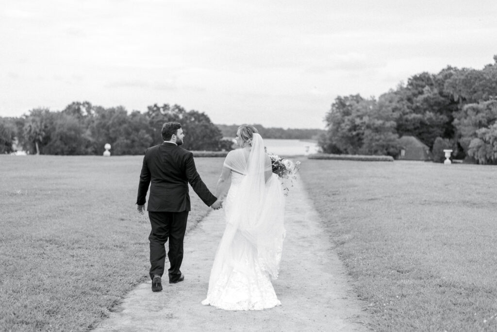 Bride and groom walk through the butterfly garden at middleton place