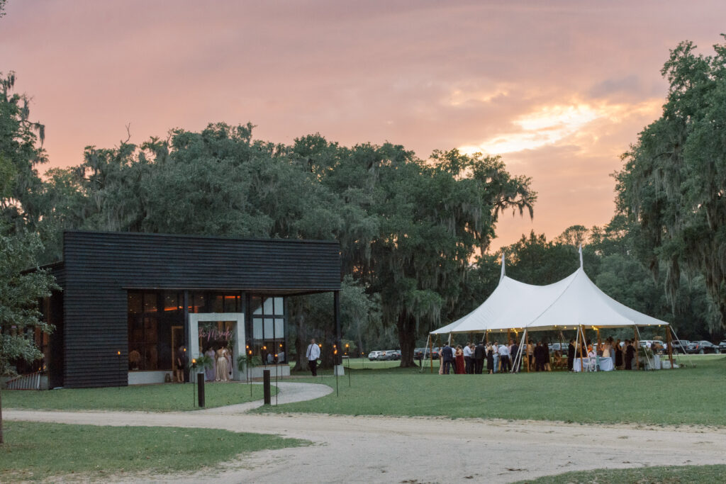 Sunset photo of a wedding reception setup under a sailcloth tent at Middleton Place