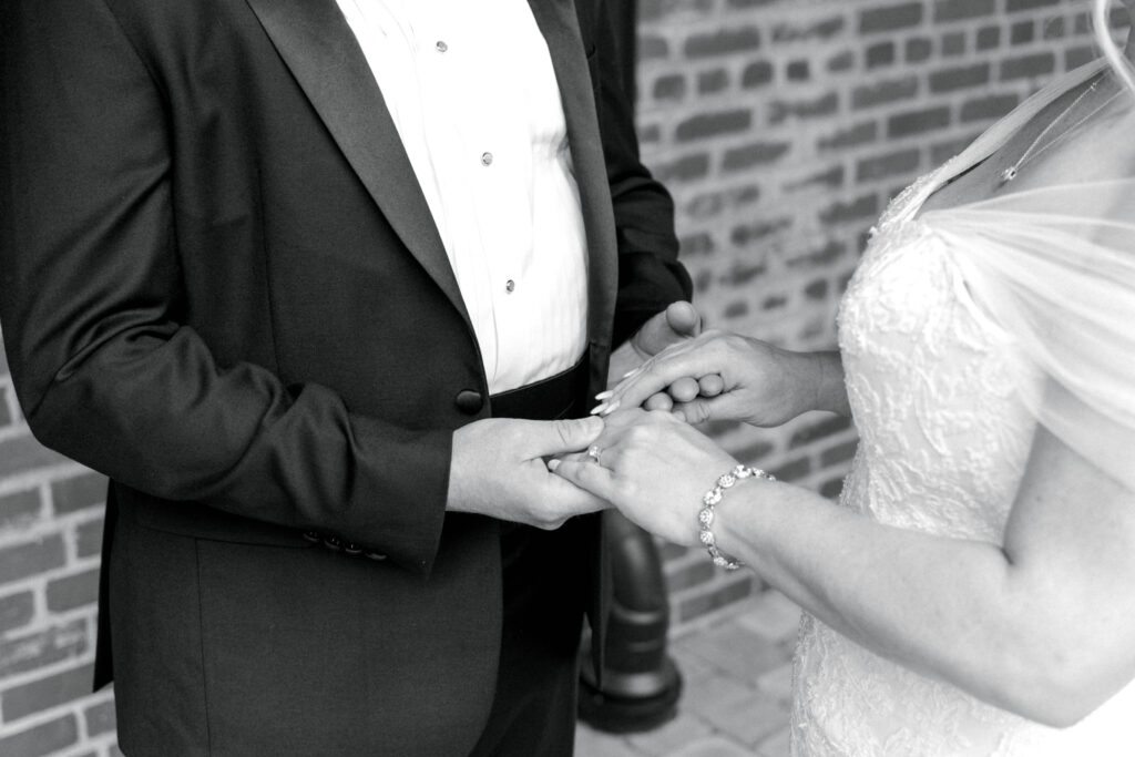 close up of bride and groom holding hands in black and white