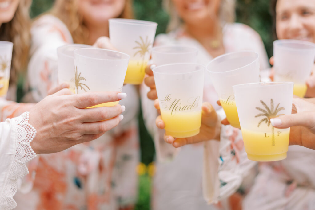 Bridesmaids and bride cheers with personalized cups filled with mimosas 