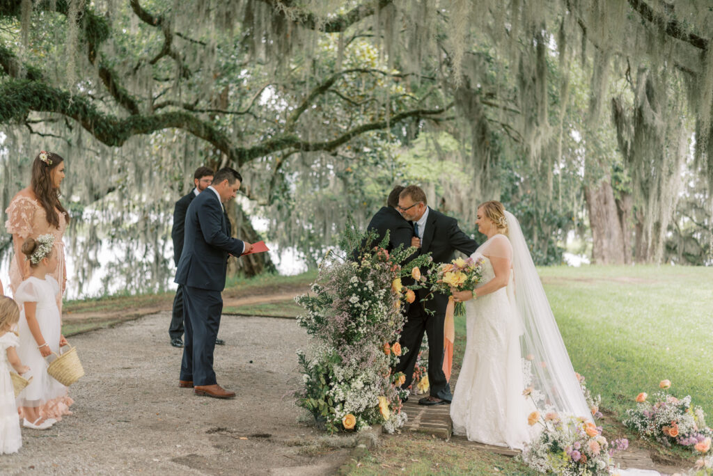 Bride's father gives her away between pillars of flowers