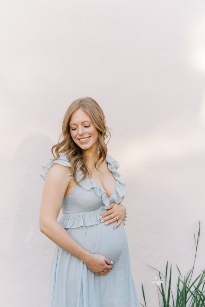 maternity portrait of a woman in a blue dress with ruffled neckline