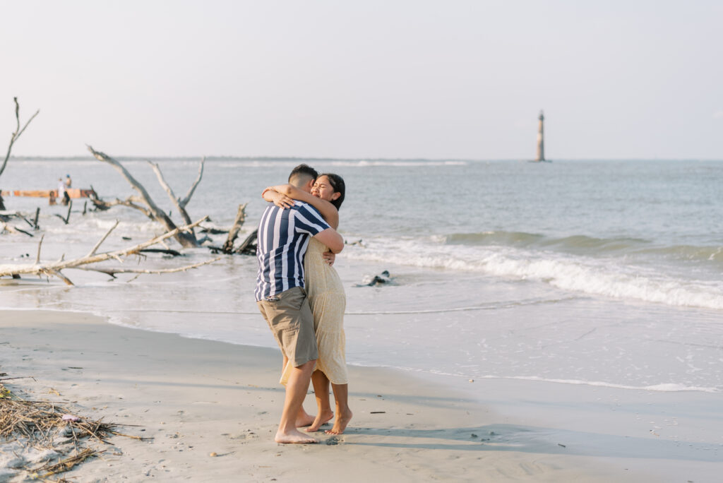 Couple hugging after getting engaged at Folly Beach in the evening