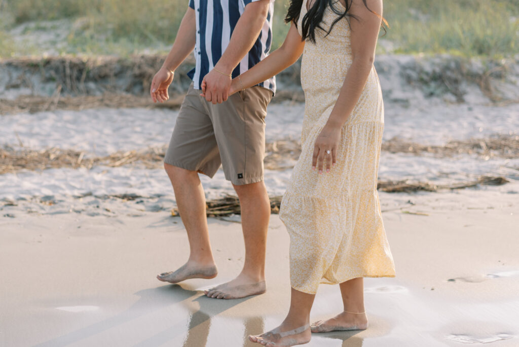 close up of couples holding hands walking on the beach