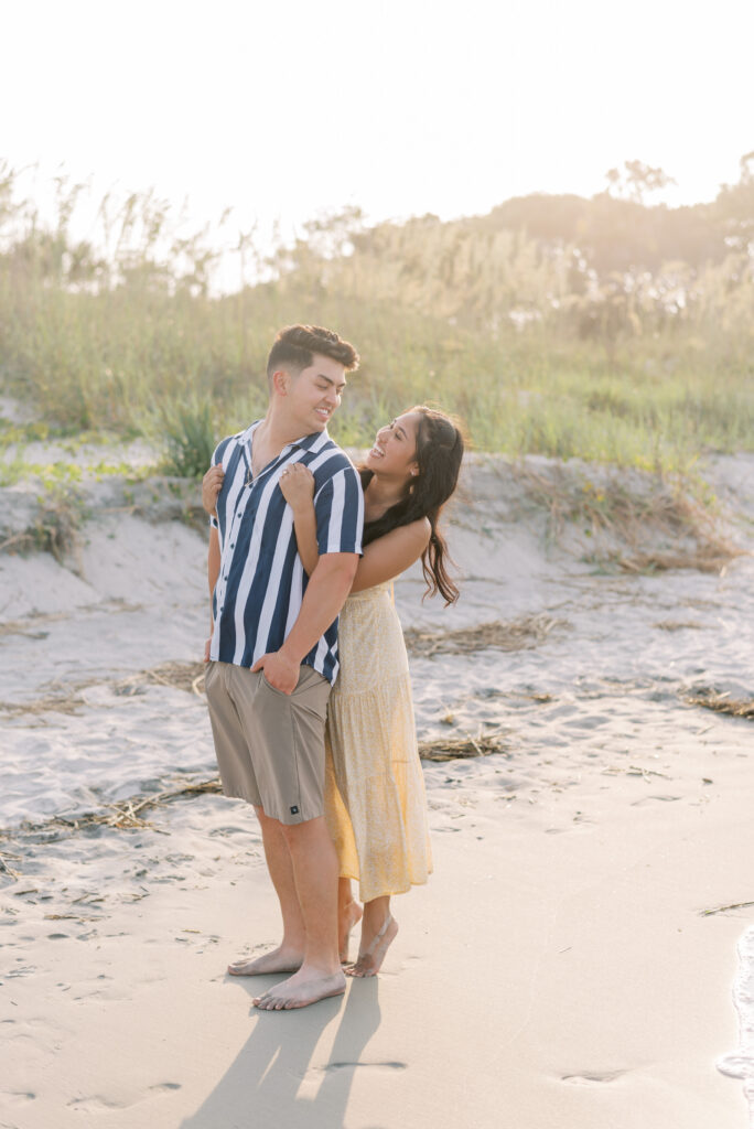 newly engaged couple hug on the beach at sunset