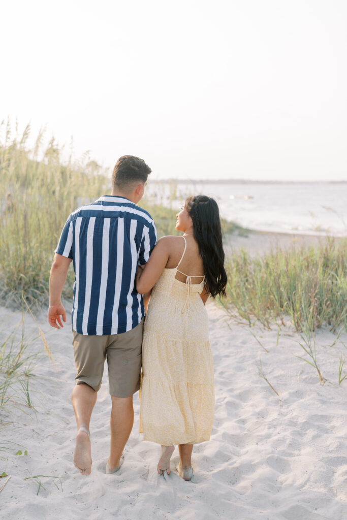 couple holding close together and walking away from the camera on the beach