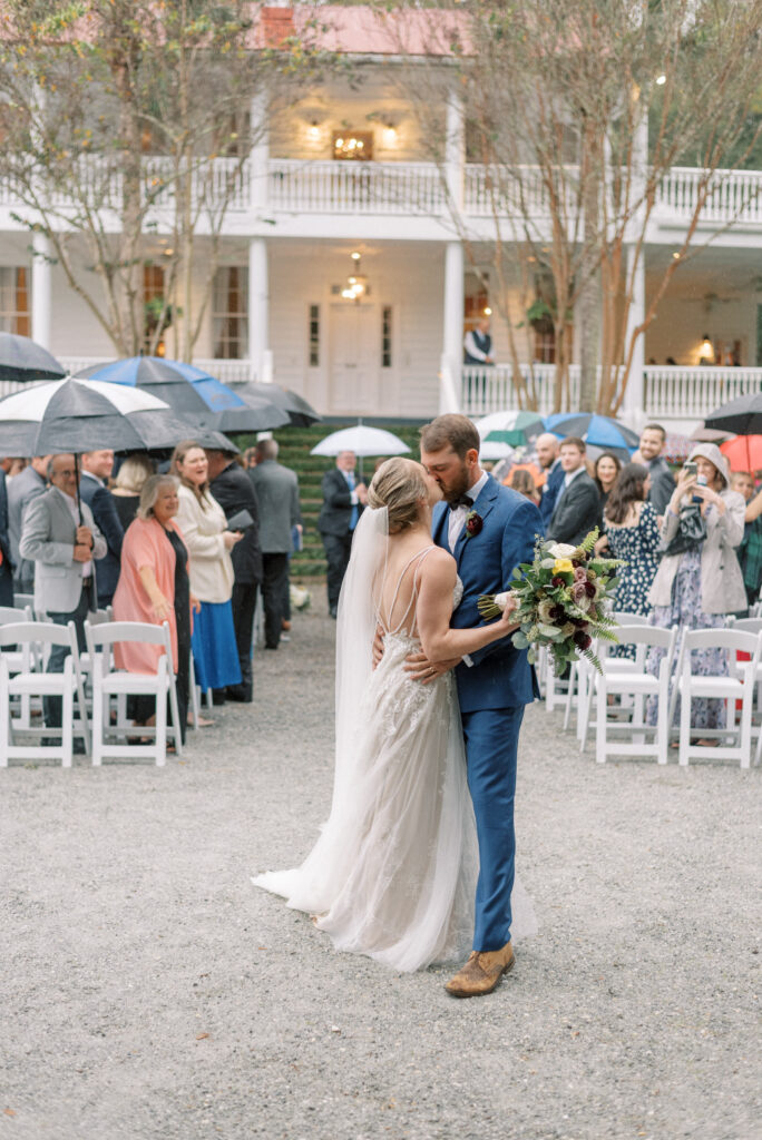 Bride and groom share a kiss during their rainy wedding ceremony at Old Wide Awake