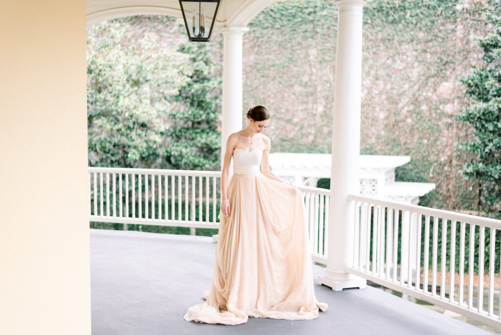 Bride fixes her gown on the terrace at William Aiken House in Charleston South Carolina