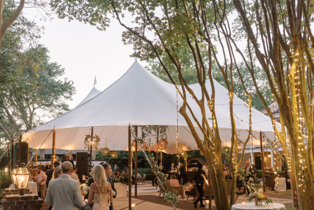 Sailcloth tent with twinkle lights and wicker chandeliers and greenery at a Charleston wedding