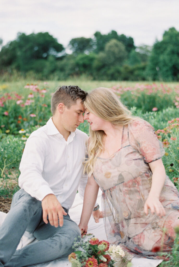 Couple lean close together sitting amid the flowers
