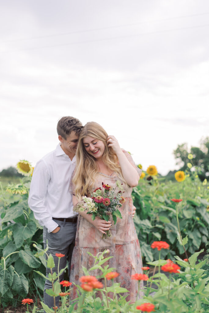 couple standing in a flower field laughing together