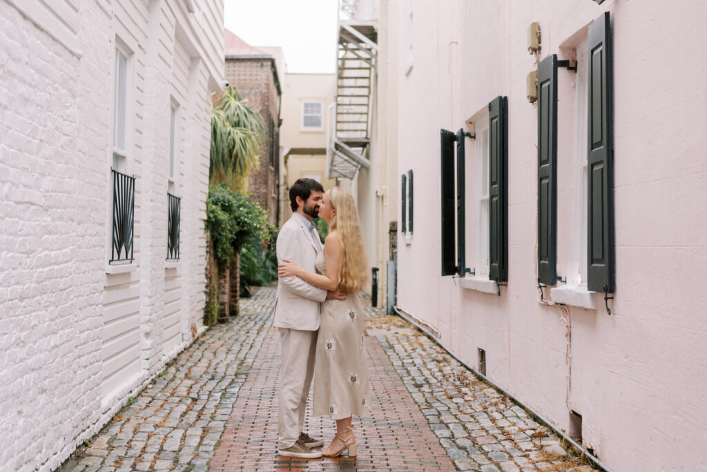 Couple snuggle together in a brick alley in downtown Charleston during engagement photos 