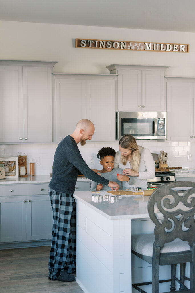 family bakes cookies together at their kitchen island all wearing pajamas