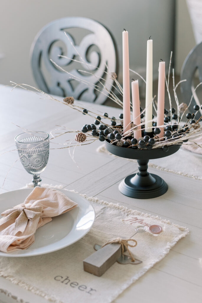 neutral Christmas table centerpiece with blush and ivory candles and a black base