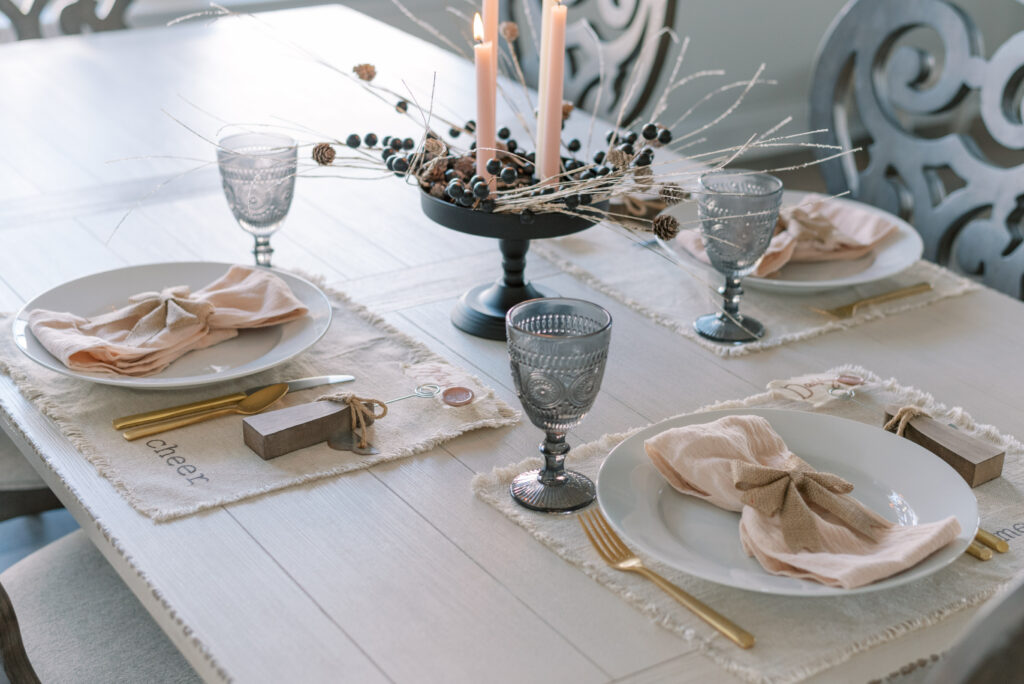 table set for three with neutral christmas place settings white ivory smoked glass and black centerpiece
