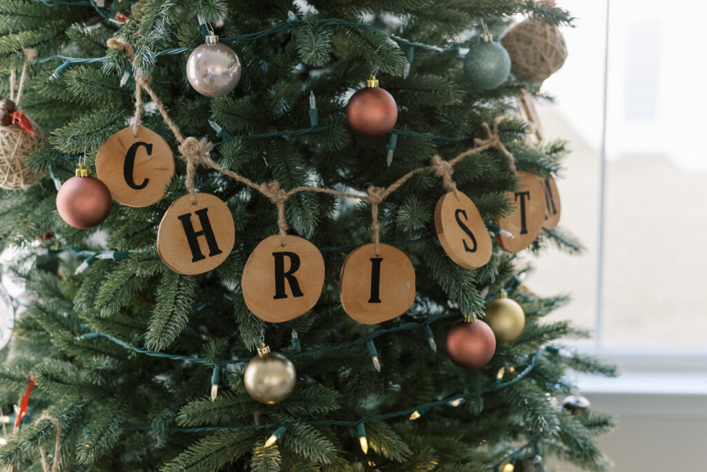 wooden christmas sign hung on twine on a christmas tree