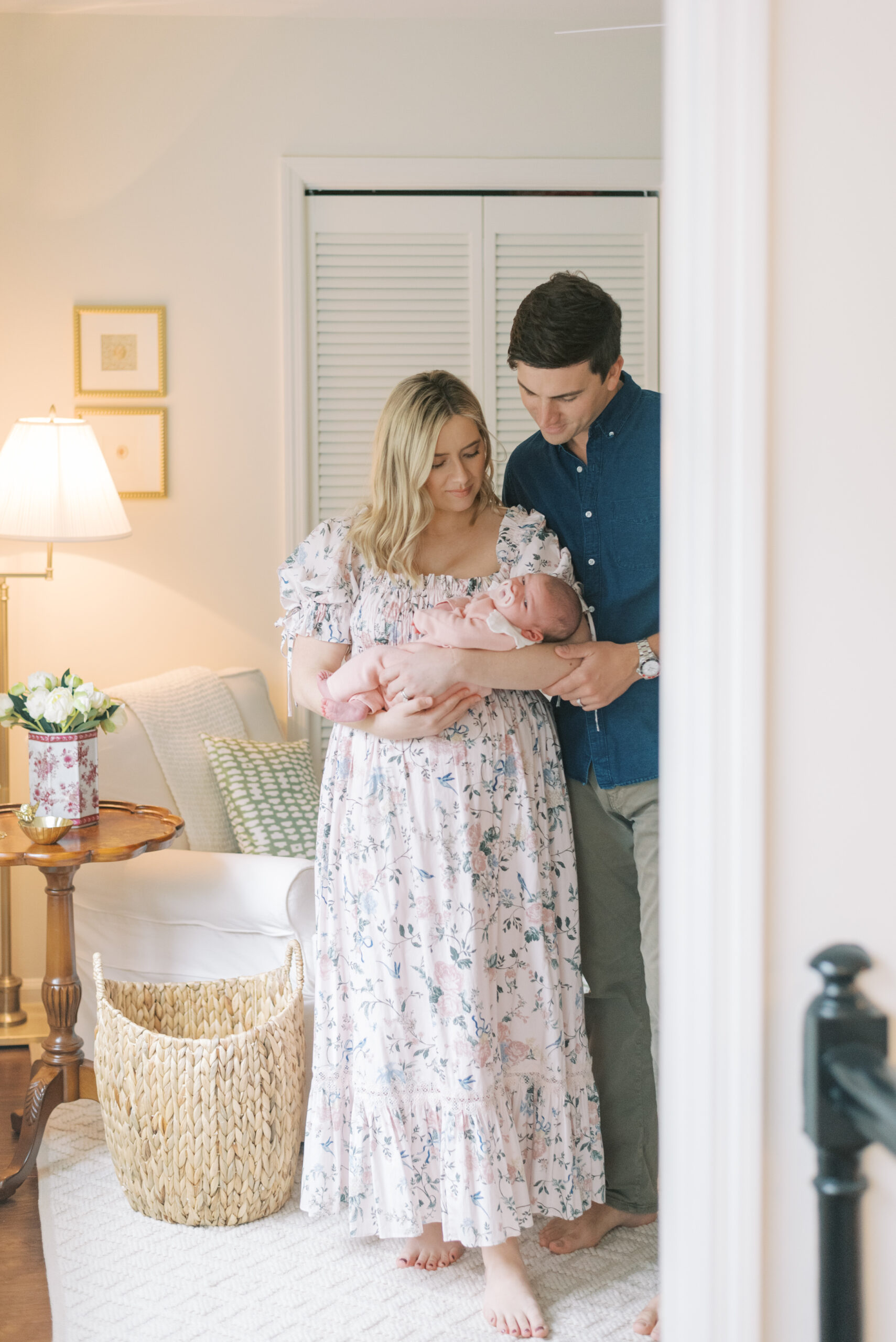 Mother holding her newborn baby by a sunlit window during a cozy in-home lifestyle newborn session in Charleston, SC, capturing the tender early days of family life.